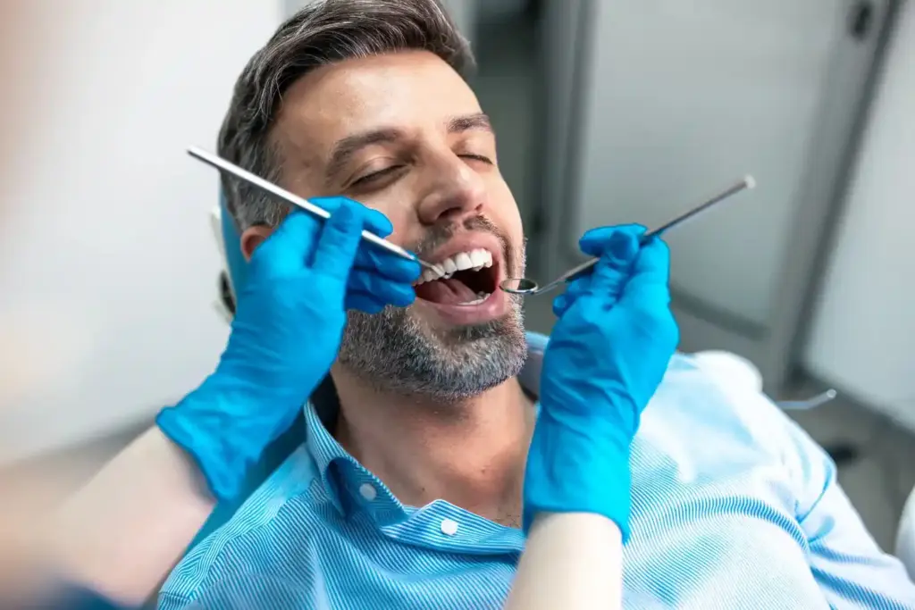 Patient receiving a routine dental checkup as a dentist examines teeth with dental instruments during a preventive dental exam